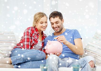 坐在沙发上的一对笑着的夫妇和小猪银行女士薪水保险收益财政预算夫妻硬币金融已婚图片