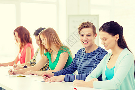 学校里带着课本 微笑着笑着的学生学者教育写作学习团体课堂测试家庭作业男孩们女性图片