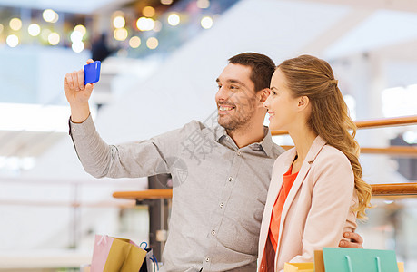 快乐的情侣与智能手机 在商场自拍家庭顾客电话男人朋友们牙裔购物中心男朋友零售购物狂图片