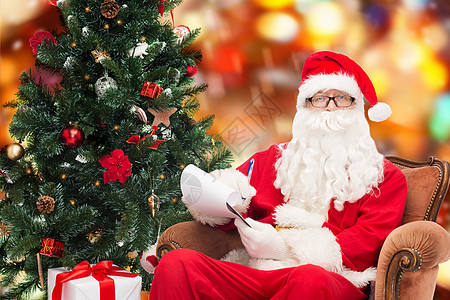 圣诞节狂欢穿着圣塔的装扮和笔记本的人男人笔记写作胡须老年男性假期庆典扶手椅快乐背景