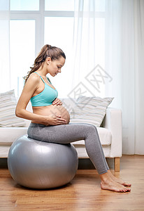 夜空月幸福的孕妇在家里健身球上锻炼保健女士体操女性平衡训练母性婴儿生活怀孕背景
