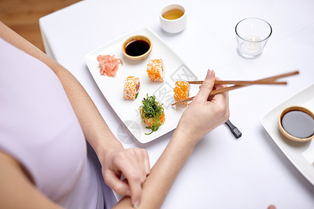 在餐厅吃寿司的近身女人享受筷子海鲜女孩厨房盘子食物一部分女士桌子图片