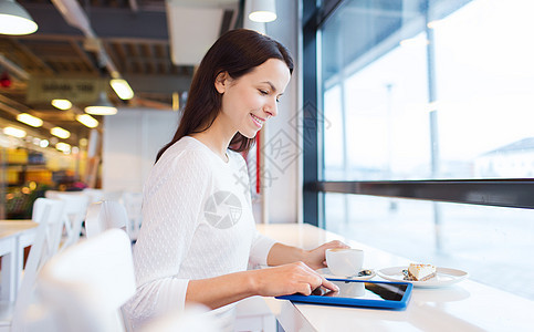 在咖啡厅里用平板电脑和咖啡的 微笑着的女人休息女孩女士女性上网技术快乐闲暇午餐时间图片