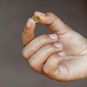 年轻女孩持有的鱼油药丸营养食物凝胶养分鳕鱼节食身体金子消化药店图片