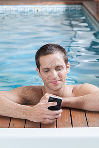 人在游泳池里玩细胞游戏温泉水池男性屏幕假期蓝色手机边缘财产肖像图片
