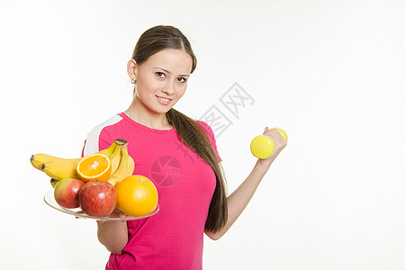 持有水果和哑铃盘的女运动员图片