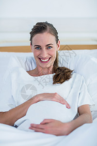 快乐的孕妇在镜头前微笑孕妇装腹部卫生孕产怀孕肚子保健枕头病人生长图片