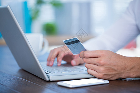 一名使用信用卡的商务人士近距离收看电脑桌子商业电话办公室技术工作网上购物职业购物图片