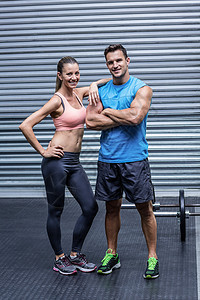 看着镜头的一对微笑的肌肉夫妇女性闲暇健身房男性班级身体中心女士培训师健身室图片