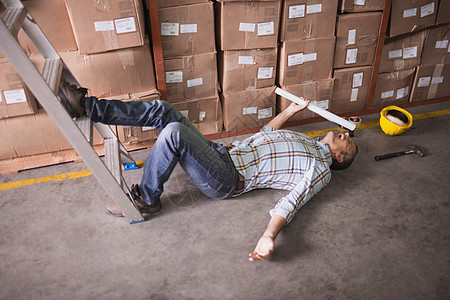 工人躺在仓库的地板上盒子贮存梯子事故货物安全危险配送说谎库存图片