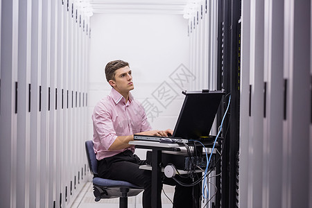 技术员坐在使用膝上型电脑诊断服务器的旋转椅上笔记本数据中心网络中心技术路由器数据男性电线男人图片