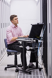 技术员坐在使用膝上型电脑诊断服务器的旋转椅上维修储物柜网络贮存数据电线中心电子产品硬件数据中心图片