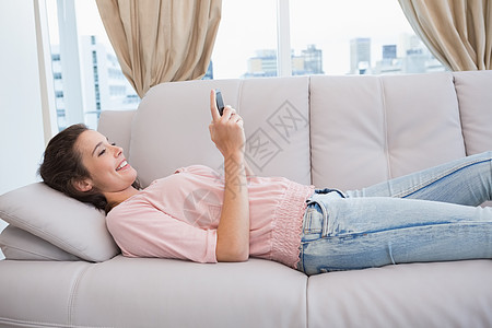 在沙发上使用智能手机的漂亮黑发美女服装短信住所棕色家庭拨号房子微笑女士头发图片
