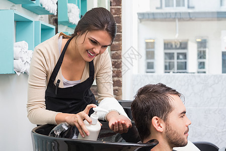 发型设计师把调理器放在男人头发上理发微笑短发工作快乐男性客户发型女士理发师图片