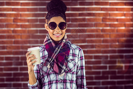 一位女性嬉皮士拿着咖啡喝着一杯咖啡微笑黑发饮料快乐格纹衬衫太阳镜长发女士围巾图片