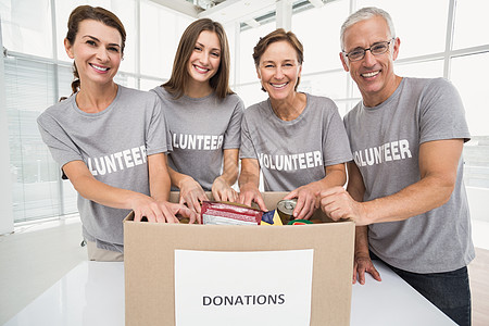 捐物资微笑的志愿人员对捐助箱进行分类捐赠办公室人士合伙团队女士商务帮助盒子志愿者背景