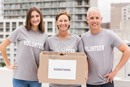 捐物资手持捐赠箱的微笑志愿者休闲职业男人人士捐赠福利服务工作女性建筑背景