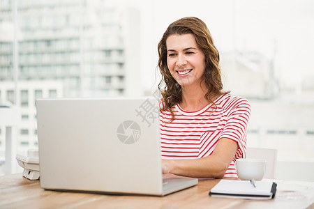 使用笔记本电脑的微笑临时临时女商务人士技术职业女士商务休闲服办公室木桌新生意快乐热饮图片