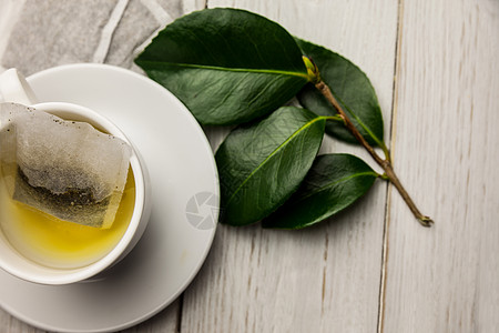 白色叶子素材杯草药茶放在桌上热饮饮食桌子抗氧化酿造白色花草绿茶木头茶包背景