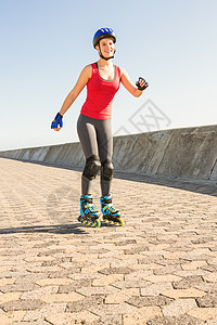 微笑运动的金发滑冰码头运动服蓝天微笑旱冰快乐活动身体长廊头盔图片