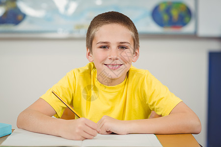 在一个教室的书桌里工作的微笑的学生幼儿园学校铅笔桌子学习童年男性男生教育小学图片
