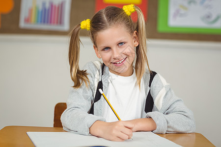 在她办公室的教室里工作的可爱学生微笑小学生女孩写作童年瞳孔记事本课堂学习智力图片