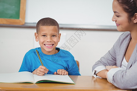 在老师帮助下 微笑的学生得到教师的帮助学习混血瞳孔头发童年桌子早教教学小学生课堂图片