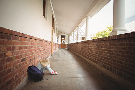 孤单坐在地上的悲惨学生小学教育哭泣悲伤小学生孤独女孩学校寂寞女性图片