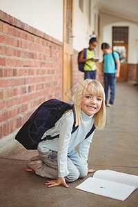 可爱的学生跪在走廊的笔记板上同学们小学学校微笑知识记事本班级小学生门厅朋友图片