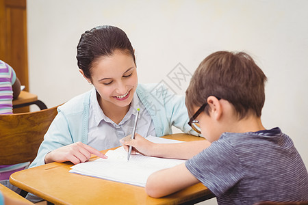 老师在课堂上帮助一个小男孩早教女性男生工作童年写作小学瞳孔椅子教学图片