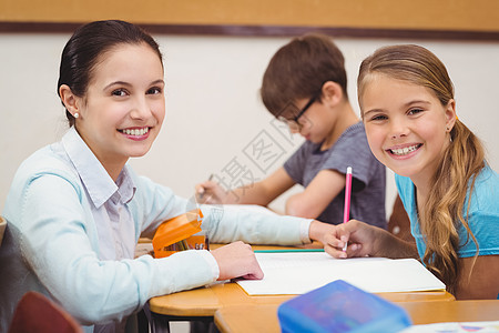 在课堂上帮助一个小女孩的老师微笑教育工作班级男性童年女孩孩子学校教学图片