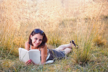女人躺在草地上看书教科书学生快乐女孩文学阅读黑发女士公园大学图片