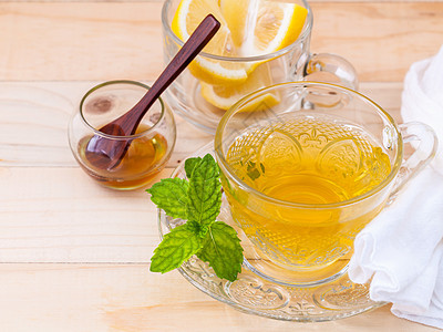 一杯草药茶 鲜绿色薄荷 蜂蜜和柠檬加木头草本植物植物药品芳香水果杯子饮料液体烹饪康复图片