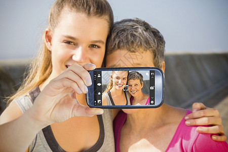 手持智能手机显示的复合图象相机家庭女儿运动服护理感情女性展示长廊蓝天图片