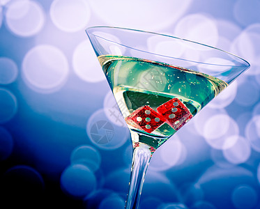 鸡尾酒杯中的红色骰子 在蓝色的bokeh上钻石优胜者嘶嘶金子背景游戏扑克娱乐桌子气泡图片