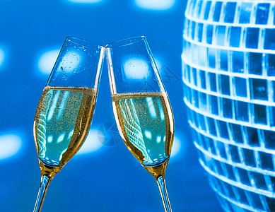 一对香槟笛子 配有金泡泡 在闪亮的蓝色迪斯科舞团背景上欢呼图片