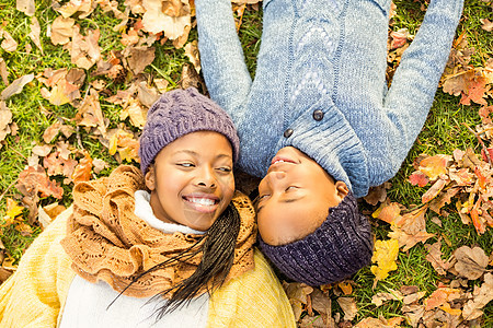 年轻母亲与女儿躺在树叶上绿地女性童年草地微笑公园草原幸福衣服活动图片