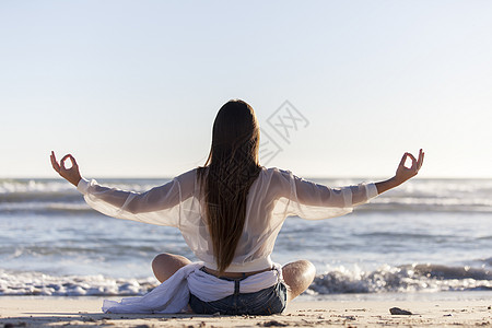 女人在海滩上做瑜伽牛仔裤运动女孩阴影海洋太阳身体女性姿势成人图片