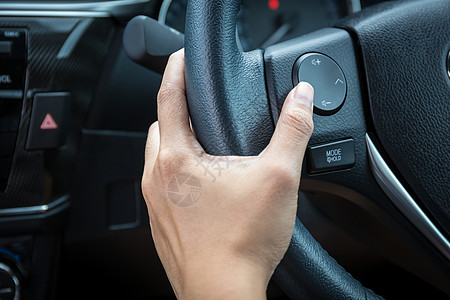 一位女性手推着方向盘上的音量控制按钮巡航司机力量展示女士汽车控制板功能车轮减速图片