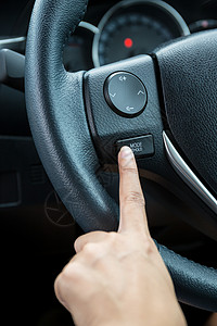 一个女人手推着模式 按住方向盘上的控制按钮车辆运输驾驶司机控制板速度减速汽车拇指奢华图片