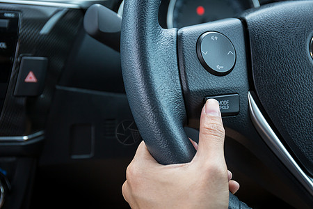 一个女人手推着模式 按住方向盘上的控制按钮功能驾驶皮革力量车辆女士司机奢华速度减速图片