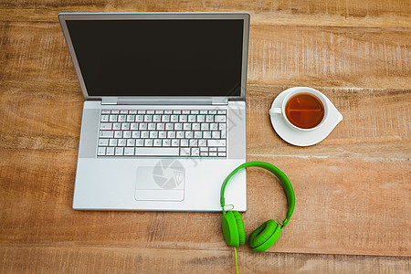 使用绿色耳机的灰色笔记本电脑视图木头技术饮料工作热饮桌子休息图片