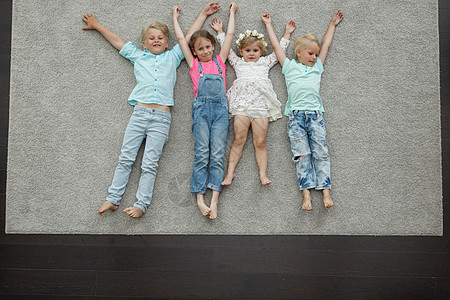 孩子们躺在地板上男生微笑朋友们团体地面金发女孩快乐朋友地毯背景图片
