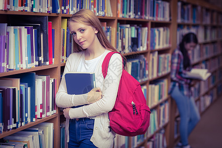 微笑的学生靠在书架的对面倾斜高等教育青少年混血知识服装女士校园教育休闲图片