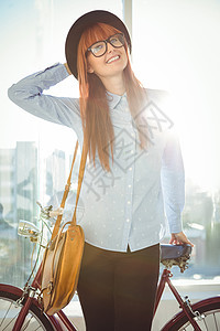 仰着自行车微笑的潮人女人女性红发快乐服装女士刘海休闲眼镜城市边缘图片