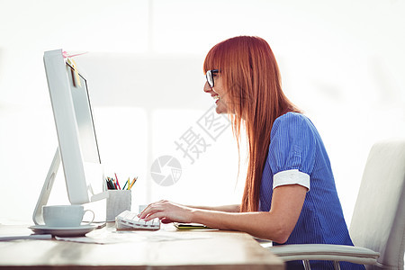 在键盘上打字的笑笑时髦女人微笑快乐眼镜桌子咖啡机构技术商业工作专业图片