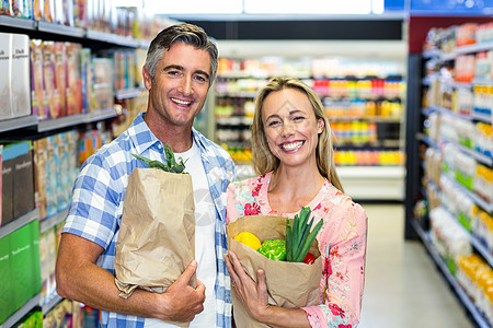 带杂货袋的一对微笑的情侣零售男性成人饮食市场顾客快乐产品女性休闲图片
