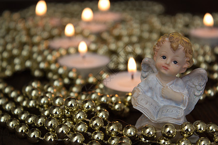 圣诞天使在蜡烛背景的圣诞天使钟声金子酒杯珠子桌子季节装饰品框架玻璃假期图片