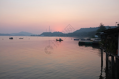 日落后海滩码头的海和山戏剧性天空海洋太阳支撑岛屿港口反射海岸场景图片