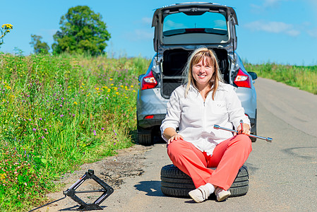 坐在破车附近轮椅上快乐的女司机图片
